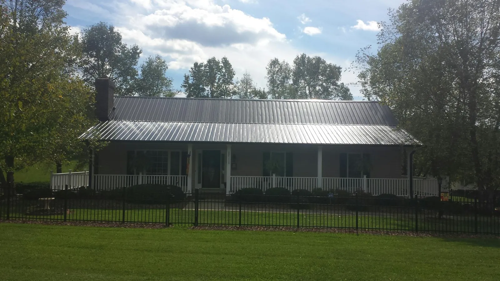 Gray metal roof on a brick ranch with a full width front porch — Gutter Guard Installation work by our crew in Mendon